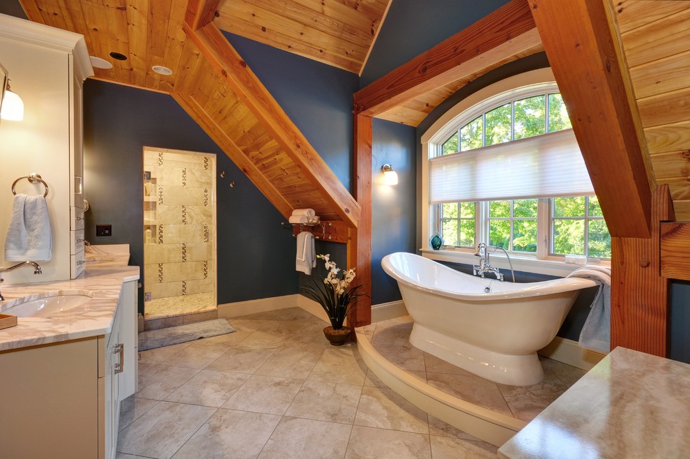 Inspiration pour une salle de bain traditionnelle avec des portes de placard blanches, une baignoire indépendante, un carrelage beige, un carrelage gris, un mur bleu, un lavabo encastré et un sol beige.