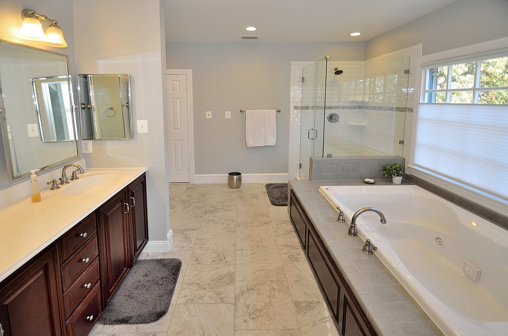 Foto di una stanza da bagno classica con lavabo integrato, ante con bugna sagomata, vasca da incasso, doccia ad angolo, WC a due pezzi, piastrelle grigie e piastrelle a mosaico