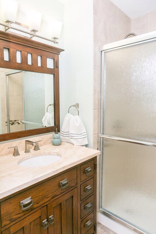 Ejemplo de cuarto de baño tradicional pequeño con armarios estilo shaker, puertas de armario de madera en tonos medios, ducha empotrada, paredes blancas, aseo y ducha, lavabo bajoencimera y encimera de piedra caliza