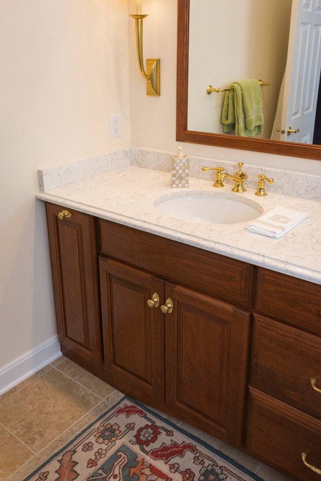 Photo of a medium sized traditional ensuite bathroom in Cincinnati with raised-panel cabinets, medium wood cabinets, a corner shower, a one-piece toilet, beige tiles, porcelain tiles, beige walls, porcelain flooring, a submerged sink, quartz worktops, beige floors and a hinged door.