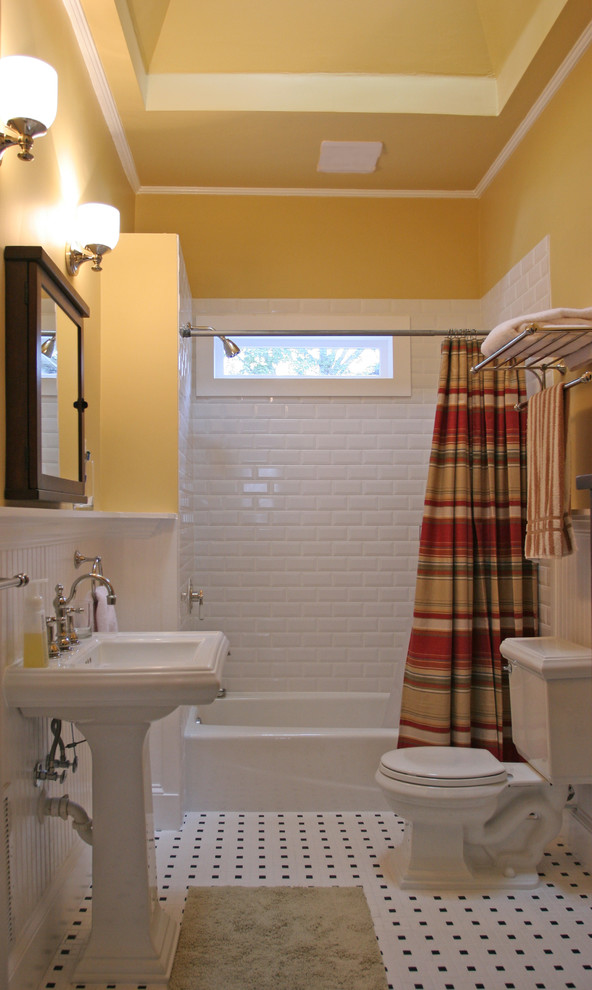 На фото: ванная комната: освещение в классическом стиле с раковиной с пьедесталом, желтыми стенами, ванной в нише, душем над ванной, белой плиткой, плиткой кабанчик и разноцветным полом