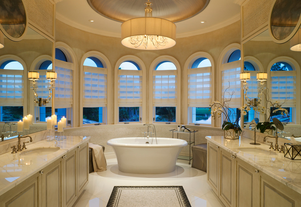 Exempel på ett stort klassiskt en-suite badrum, med ett undermonterad handfat, ett fristående badkar, luckor med upphöjd panel, beige skåp, beige kakel, mosaik, beige väggar, klinkergolv i keramik, marmorbänkskiva och vitt golv