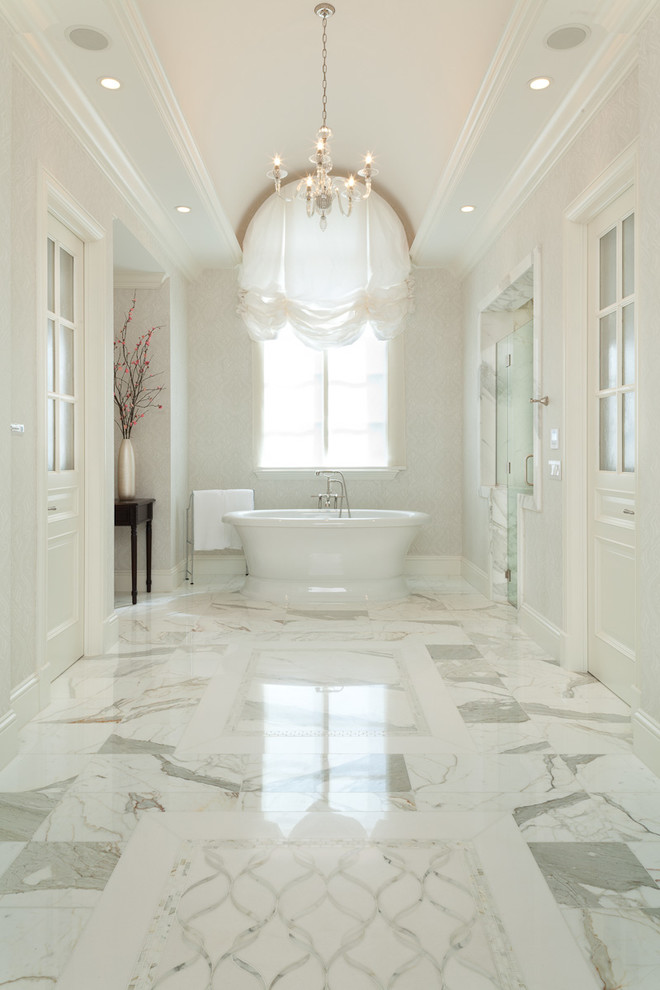Großes Klassisches Badezimmer En Suite mit freistehender Badewanne, weißen Fliesen, Marmorboden, profilierten Schrankfronten, weißen Schränken, Duschnische, Marmorfliesen, beiger Wandfarbe, Marmor-Waschbecken/Waschtisch, weißem Boden und Falttür-Duschabtrennung in Miami