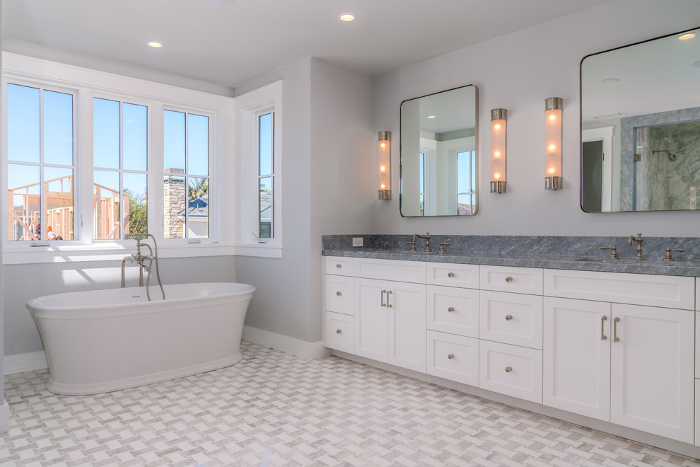 Classic bathroom in Orange County with shaker cabinets, white cabinets, a freestanding bath, grey walls, a submerged sink, grey floors and grey worktops.