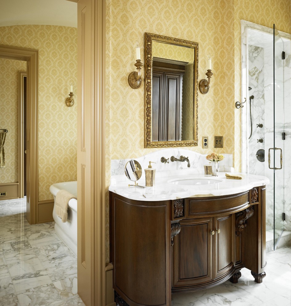 Modelo de cuarto de baño clásico con lavabo bajoencimera, puertas de armario de madera en tonos medios, bañera exenta y paredes beige