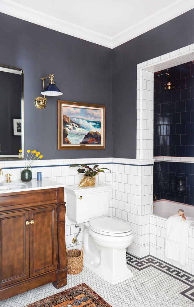 Cette image montre une salle de bain principale traditionnelle en bois brun de taille moyenne avec un placard avec porte à panneau encastré, une baignoire posée, un combiné douche/baignoire, WC à poser, un carrelage noir et blanc, un carrelage métro, un mur gris, un sol en marbre, un lavabo encastré et un plan de toilette en marbre.