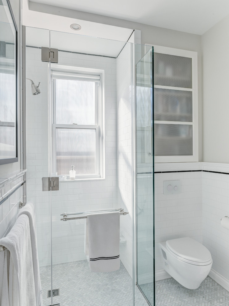 Photo of a medium sized classic shower room bathroom in New York with freestanding cabinets, white cabinets, a corner shower, a wall mounted toilet, white tiles, metro tiles, beige walls, marble flooring, a submerged sink, marble worktops, grey floors and a hinged door.