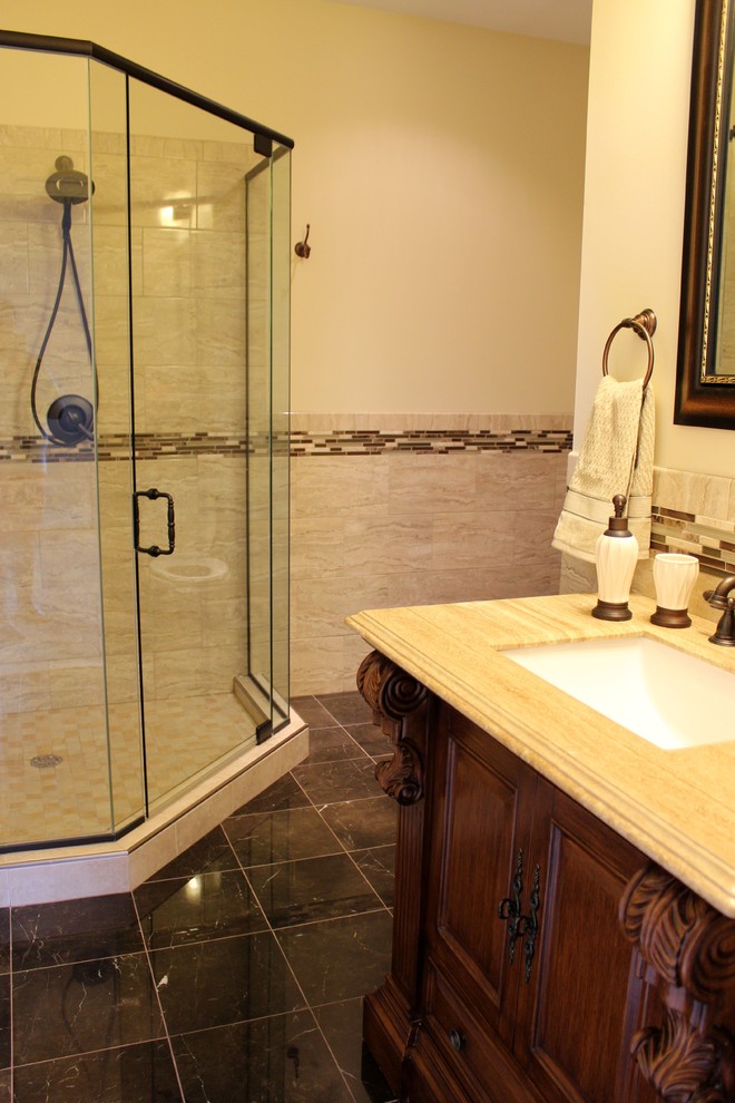 Traditional bathroom in Baltimore with raised-panel cabinets, brown cabinets, a corner shower, porcelain tiles, marble flooring, a submerged sink, brown floors and a hinged door.