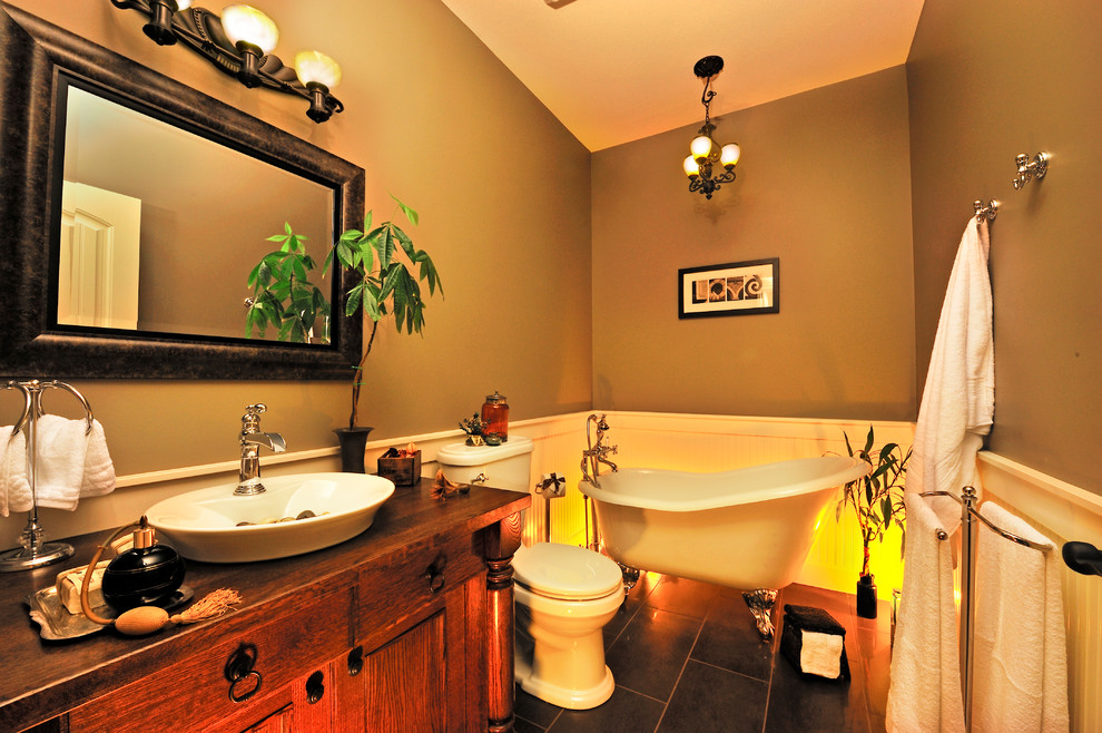 Exemple d'une salle de bain chic en bois brun avec une vasque, un placard en trompe-l'oeil, un plan de toilette en bois, une baignoire sur pieds, WC séparés, un carrelage marron et des carreaux de céramique.