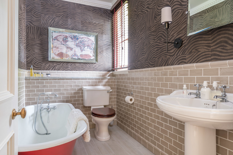 Cette photo montre une salle de bain chic avec un lavabo de ferme, une baignoire sur pieds, WC séparés, un carrelage beige et un carrelage métro.