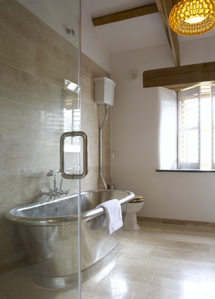 Idée de décoration pour une salle de bain tradition de taille moyenne avec une baignoire indépendante, un combiné douche/baignoire, un carrelage beige, un carrelage de pierre, un mur beige, WC à poser, un sol en carrelage de porcelaine et un sol beige.