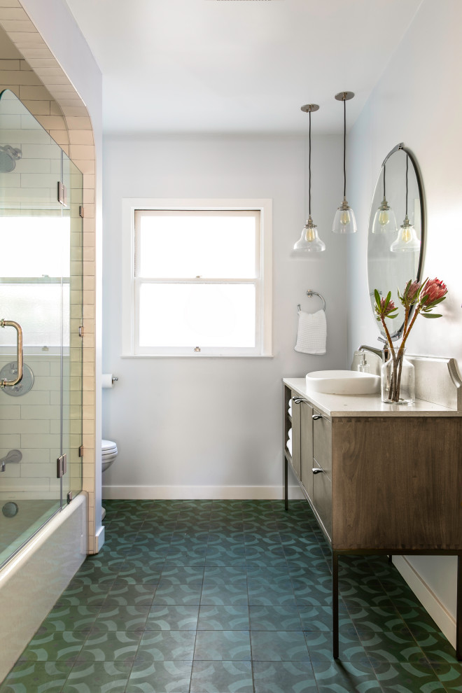 Photo of a medium sized classic shower room bathroom in San Francisco with flat-panel cabinets, brown cabinets, a built-in bath, an alcove shower, a one-piece toilet, white tiles, ceramic tiles, blue walls, cement flooring, engineered stone worktops, blue floors, a hinged door, grey worktops, a single sink and a freestanding vanity unit.