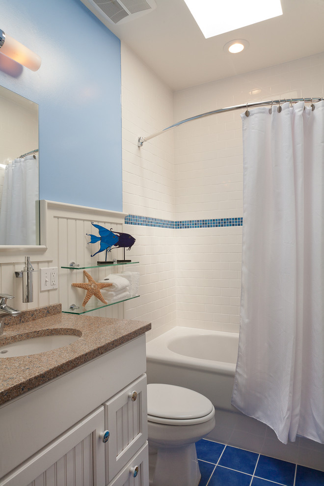 Idee per una piccola stanza da bagno per bambini costiera con vasca da incasso, vasca/doccia, WC a due pezzi, piastrelle blu, pareti blu e lavabo sottopiano