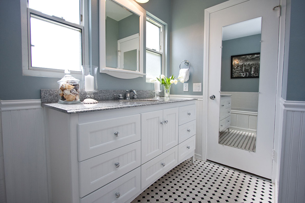 Imagen de cuarto de baño tradicional con lavabo bajoencimera, puertas de armario blancas, encimera de granito, baldosas y/o azulejos blancos, baldosas y/o azulejos de cemento, paredes azules, suelo con mosaicos de baldosas y armarios con paneles empotrados