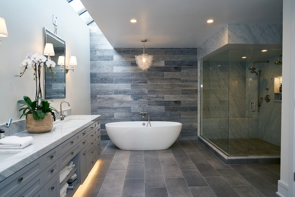 Foto på ett stort vintage badrum, med skåp i shakerstil, grå skåp, ett fristående badkar, en hörndusch, grå kakel, porslinskakel, vita väggar, ett undermonterad handfat och marmorbänkskiva