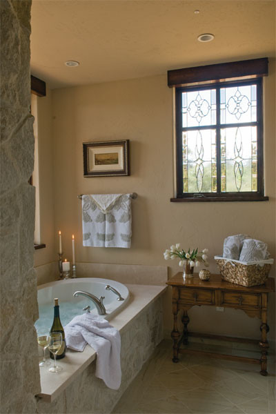Aménagement d'une grande salle de bain principale classique en bois clair avec une baignoire posée, un carrelage beige, un carrelage de pierre, un mur beige, un lavabo suspendu, un placard en trompe-l'oeil, WC séparés et tomettes au sol.