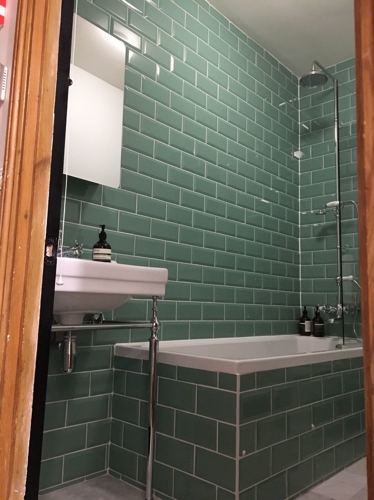 This is an example of a medium sized traditional family bathroom in London with a corner bath, a shower/bath combination, a wall mounted toilet, green tiles, ceramic tiles, green walls, marble flooring, a pedestal sink and grey cabinets.
