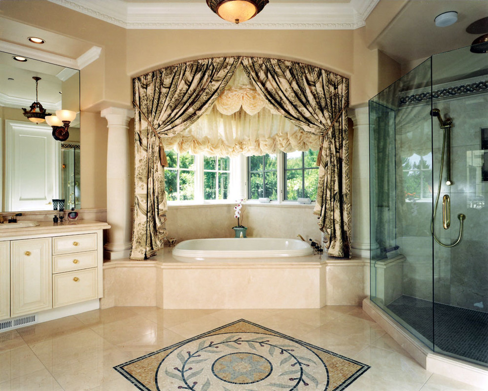 Inredning av ett klassiskt en-suite badrum, med ett nedsänkt handfat, luckor med profilerade fronter, vita skåp, marmorbänkskiva, ett platsbyggt badkar, en dubbeldusch, beige kakel, stenkakel och kalkstensgolv