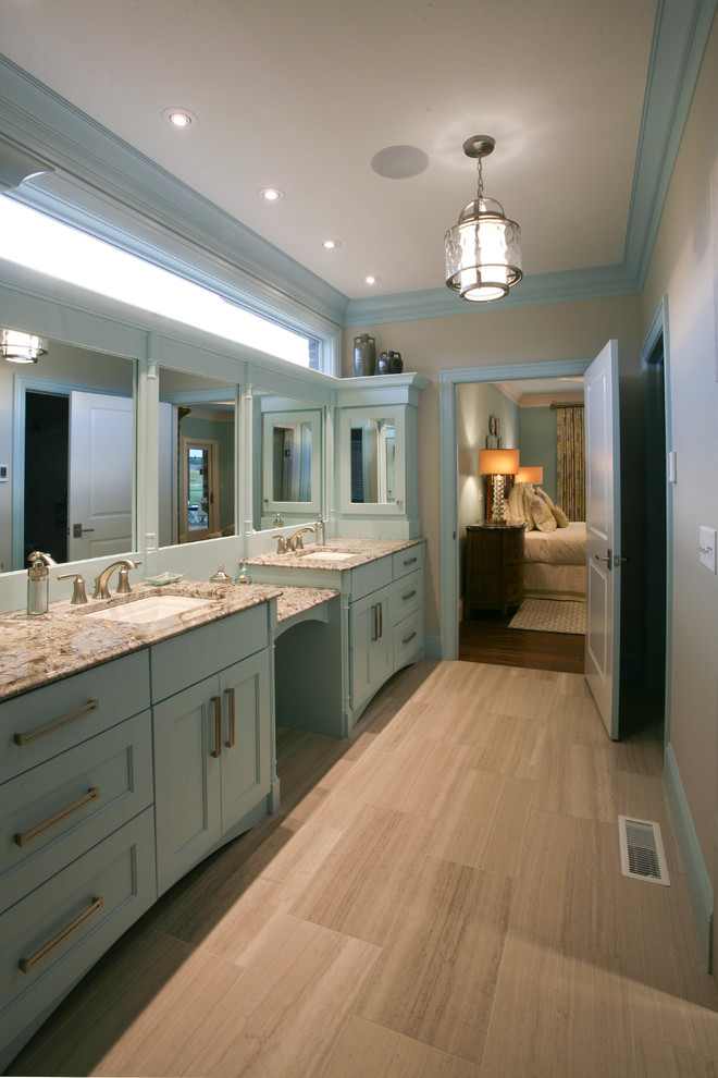 Ejemplo de cuarto de baño principal clásico grande con armarios con paneles empotrados, puertas de armario azules, paredes beige, suelo de travertino y lavabo bajoencimera
