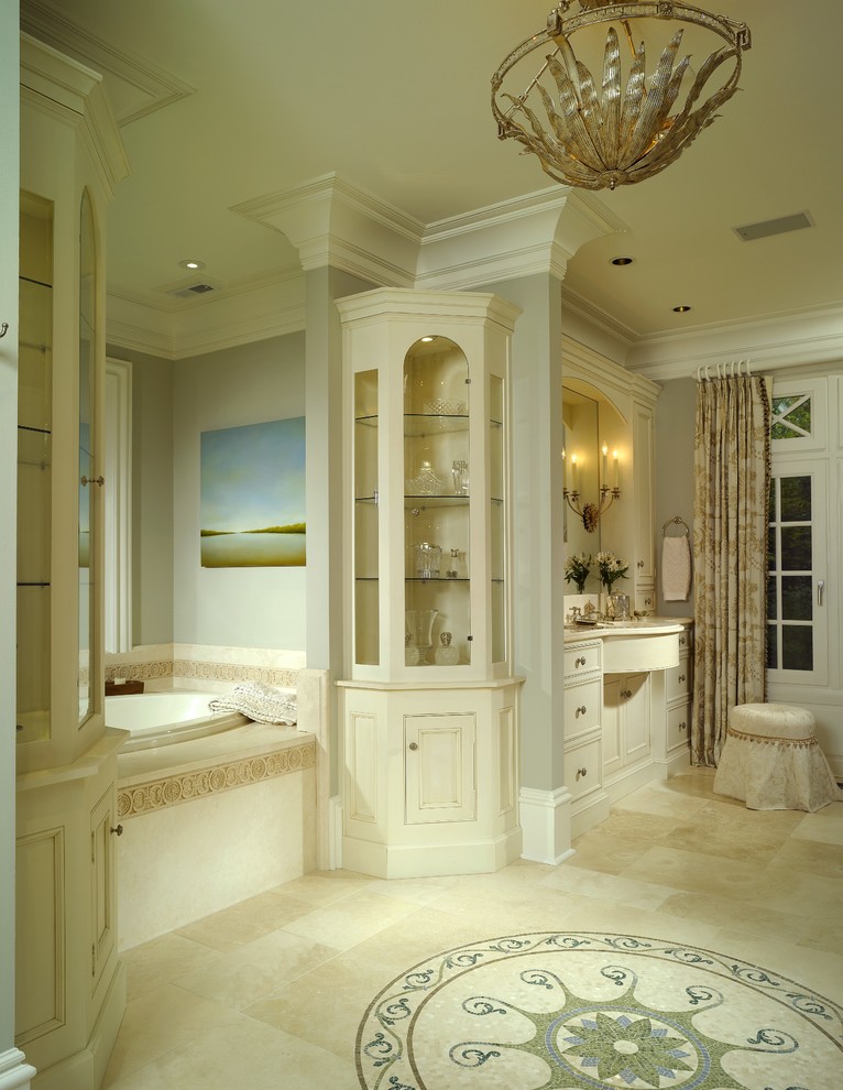 Modelo de cuarto de baño principal tradicional grande con armarios con rebordes decorativos, puertas de armario blancas, bañera encastrada, paredes grises y suelo de piedra caliza