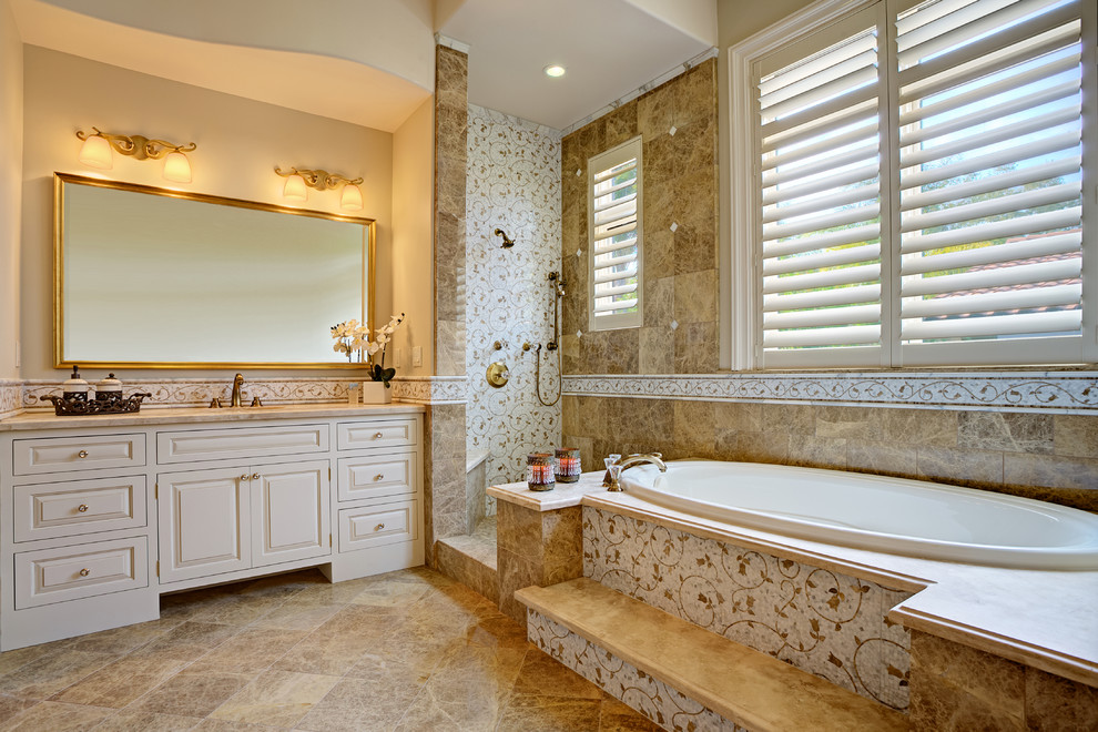 Inspiration for an expansive traditional ensuite bathroom in San Francisco with a submerged sink, beaded cabinets, white cabinets, marble worktops, a built-in bath, a walk-in shower, a one-piece toilet, brown tiles, stone tiles, beige walls and marble flooring.