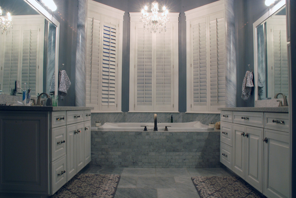 Imagen de cuarto de baño principal clásico grande con puertas de armario blancas, bañera encastrada, baldosas y/o azulejos grises, paredes grises, armarios con paneles con relieve, suelo de mármol y encimera de cuarzo compacto
