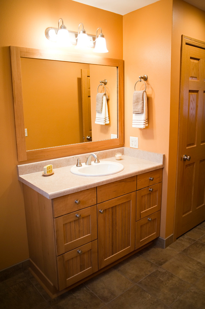 Idées déco pour une grande douche en alcôve principale classique en bois clair avec un placard à porte affleurante, une baignoire en alcôve, WC à poser, un carrelage beige, des carreaux de porcelaine, un mur orange, un sol en carrelage de porcelaine, un lavabo posé et un plan de toilette en stratifié.