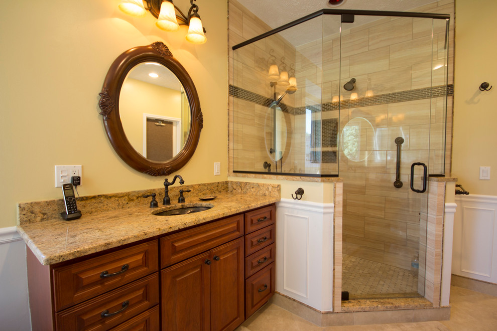 Inredning av ett klassiskt stort en-suite badrum, med skåp i mellenmörkt trä, ett badkar med tassar, en dusch i en alkov, luckor med upphöjd panel och gula väggar