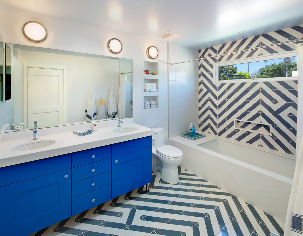 Idée de décoration pour une salle de bain bohème avec un placard à porte shaker, des portes de placard bleues, une baignoire encastrée, un combiné douche/baignoire, WC à poser, un carrelage bleu, un carrelage blanc, un mur blanc, un lavabo encastré et une cabine de douche avec un rideau.