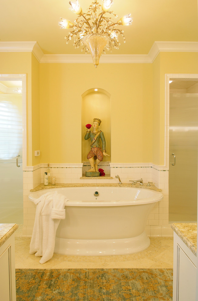 Свежая идея для дизайна: главная ванная комната среднего размера в стиле неоклассика (современная классика) с врезной раковиной, фасадами с утопленной филенкой, белыми фасадами, столешницей из гранита, отдельно стоящей ванной, душем без бортиков, унитазом-моноблоком, белой плиткой, керамической плиткой, желтыми стенами и полом из травертина - отличное фото интерьера