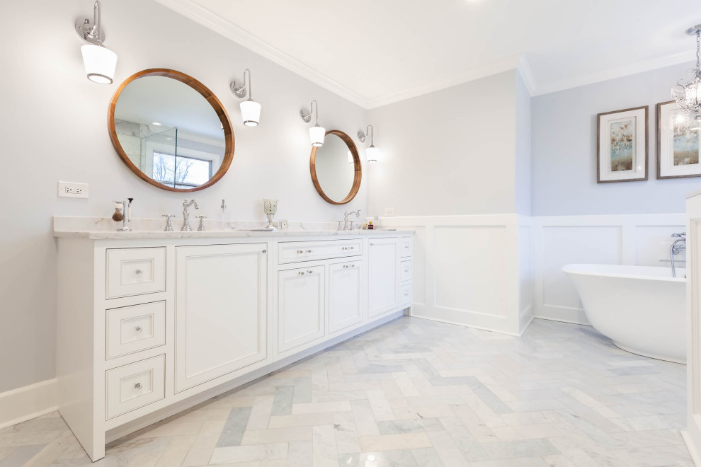 This is an example of a large traditional ensuite bathroom in Chicago with beaded cabinets, white cabinets, a freestanding bath, a corner shower, grey tiles, grey walls, marble flooring, a submerged sink, engineered stone worktops, grey floors, a hinged door, white worktops, a shower bench, double sinks, a freestanding vanity unit and wainscoting.