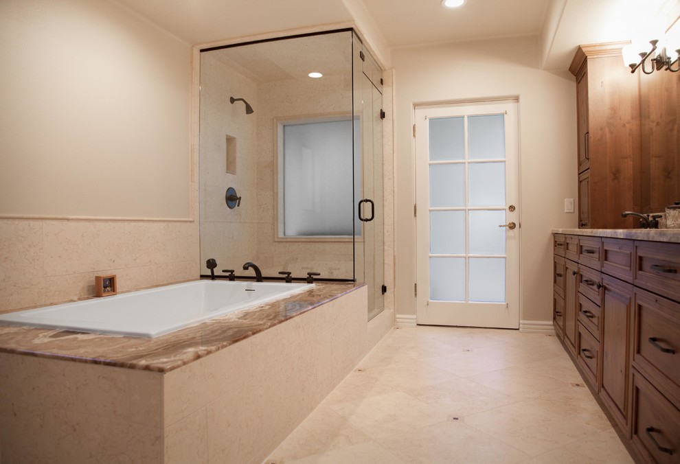 Large classic ensuite bathroom in Los Angeles with medium wood cabinets, a built-in bath, a corner shower, beige tiles, stone tiles, beige walls, marble flooring, a submerged sink and marble worktops.