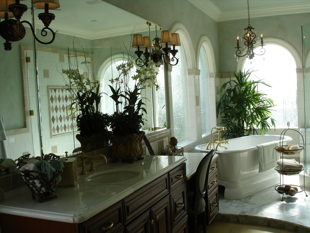 Foto på ett vintage en-suite badrum, med ett undermonterad handfat, luckor med upphöjd panel, skåp i mörkt trä, marmorbänkskiva, ett fristående badkar, vit kakel, porslinskakel, blå väggar och marmorgolv