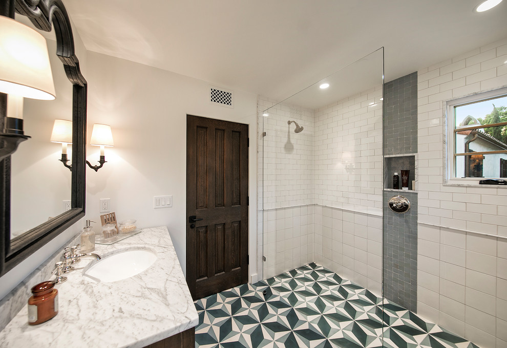 Foto på ett stort medelhavsstil badrum med dusch, med möbel-liknande, bruna skåp, en kantlös dusch, vit kakel, keramikplattor, vita väggar, cementgolv, ett nedsänkt handfat, marmorbänkskiva, flerfärgat golv och dusch med gångjärnsdörr