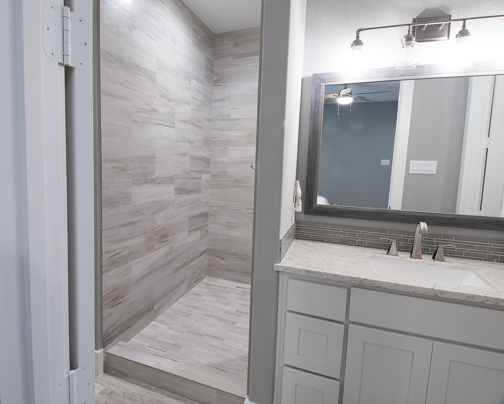 Design ideas for a medium sized traditional bathroom in Houston with recessed-panel cabinets, white cabinets, a corner shower, a two-piece toilet, grey tiles, porcelain tiles, grey walls, porcelain flooring, a submerged sink, quartz worktops, grey floors, an open shower and white worktops.
