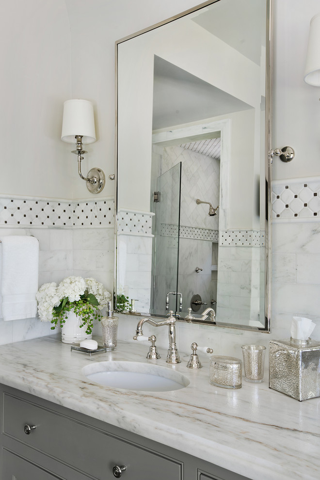 Exemple d'une salle de bain principale chic avec des portes de placard grises, un carrelage blanc, du carrelage en marbre, un plan de toilette en marbre, un mur blanc, un lavabo posé et un plan de toilette blanc.
