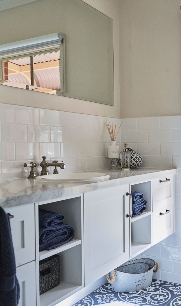Пример оригинального дизайна: главная ванная комната среднего размера в классическом стиле с фасадами в стиле шейкер, белыми фасадами, душем в нише, унитазом-моноблоком, белой плиткой, керамической плиткой, белыми стенами, полом из керамической плитки, накладной раковиной, мраморной столешницей, синим полом, душем с распашными дверями, серой столешницей, нишей, тумбой под одну раковину и встроенной тумбой