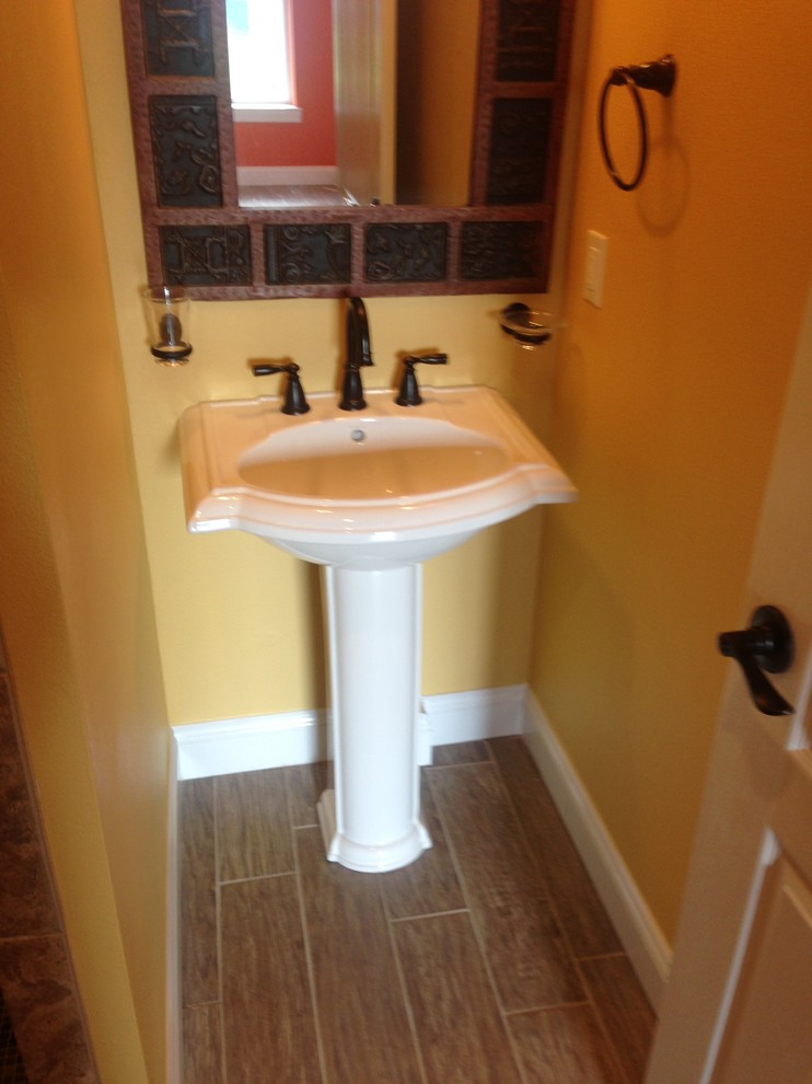 Foto på ett litet vintage badrum med dusch, med ett piedestal handfat, brun kakel, porslinskakel, gula väggar och klinkergolv i porslin
