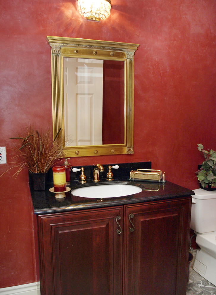 Esempio di una stanza da bagno tradizionale di medie dimensioni con ante con bugna sagomata, ante in legno bruno, WC a due pezzi, piastrelle nere, pareti rosse, lavabo sottopiano, piastrelle di marmo, pavimento in marmo e top in granito