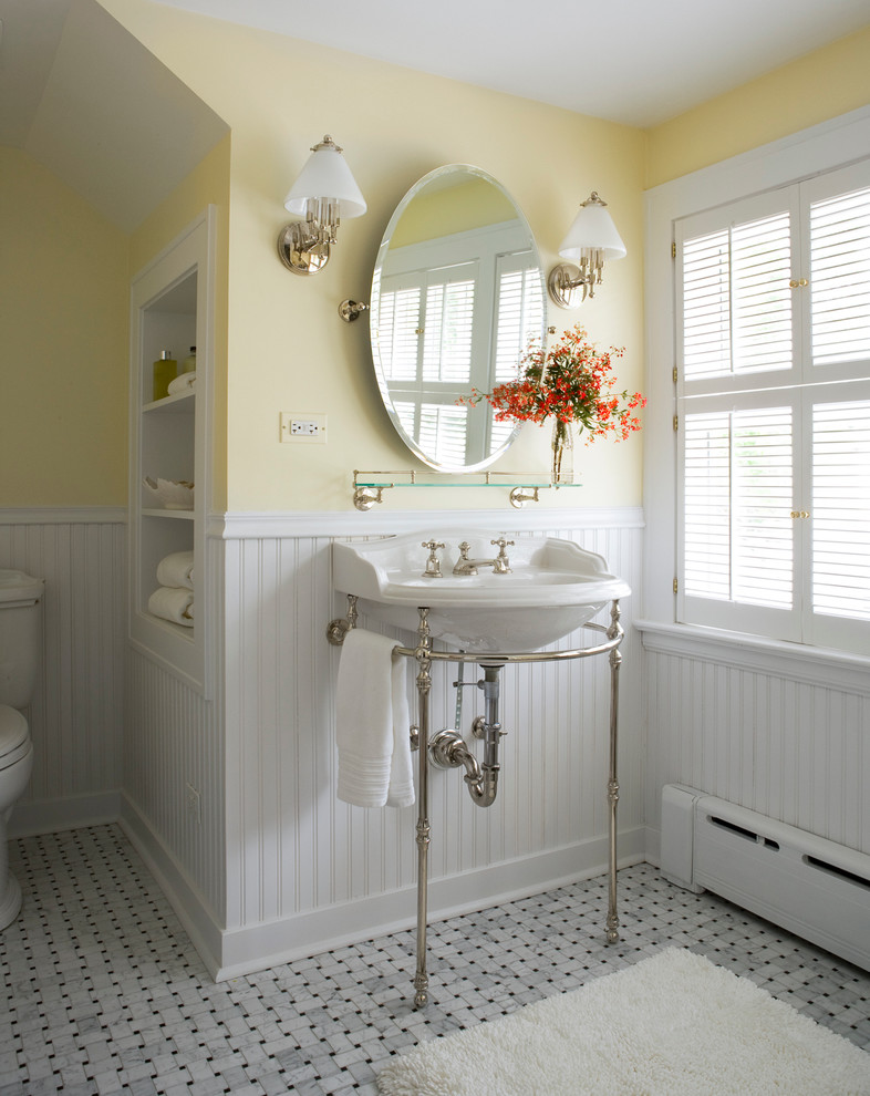 Klassisk inredning av ett badrum, med ett konsol handfat, gula väggar, mosaikgolv och grått golv