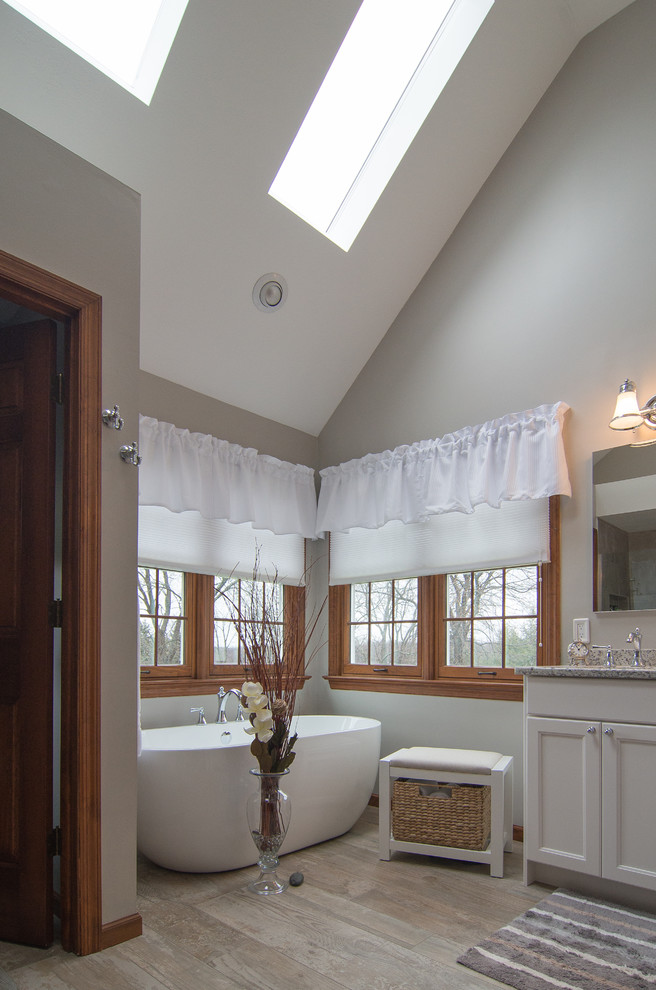 Immagine di una stanza da bagno chic con ante in stile shaker, ante bianche e vasca freestanding
