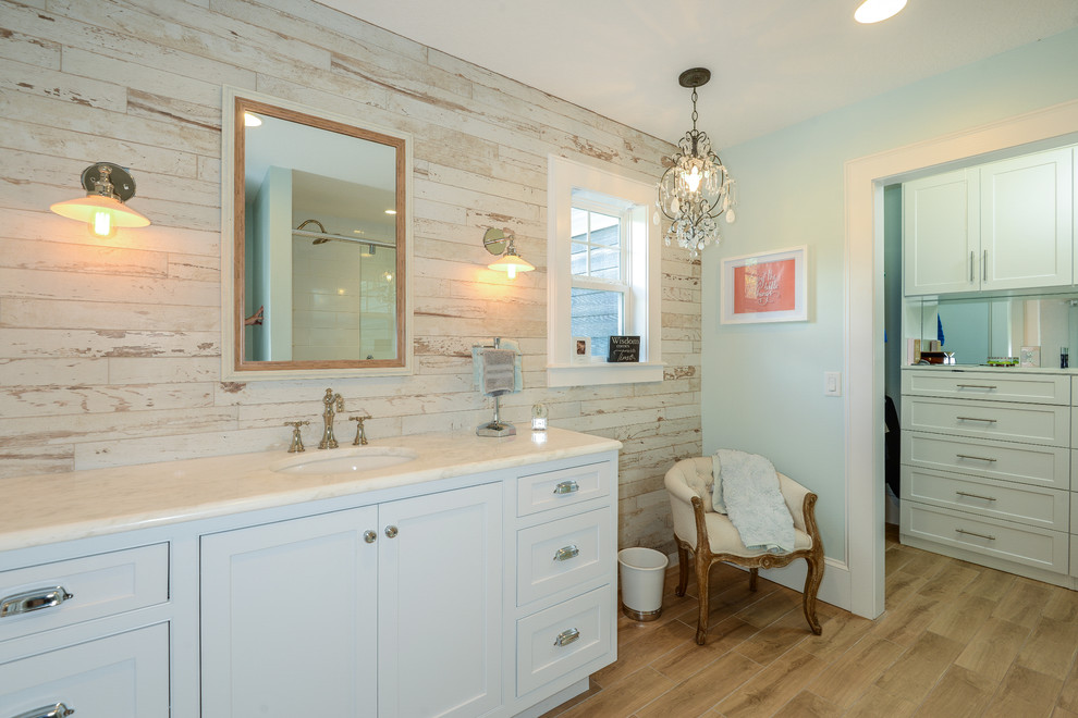 Foto de cuarto de baño tradicional pequeño con puertas de armario blancas, paredes amarillas, suelo de madera clara, lavabo bajoencimera y encimera de mármol
