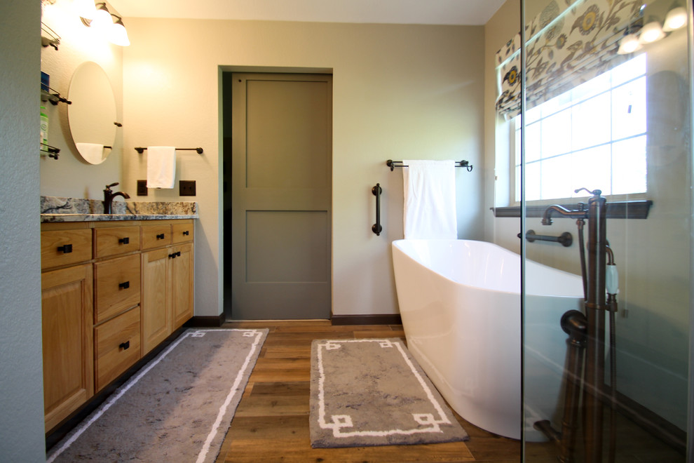 Inspiration pour une salle de bain principale traditionnelle en bois clair de taille moyenne avec un placard avec porte à panneau surélevé, une baignoire indépendante, une douche d'angle, WC à poser, un carrelage beige, des carreaux de porcelaine, un mur vert, un sol en carrelage de porcelaine, un lavabo encastré, un plan de toilette en granite, un sol marron et une cabine de douche à porte battante.
