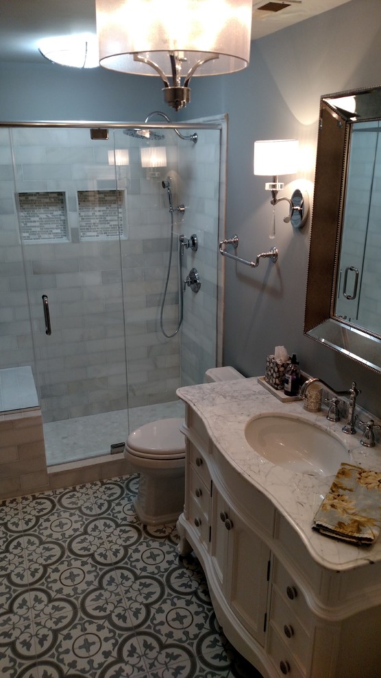 Esempio di una stanza da bagno tradizionale di medie dimensioni con doccia alcova, WC monopezzo, piastrelle bianche, piastrelle diamantate, pareti grigie, pavimento in cementine, lavabo sottopiano, top in marmo, ante con riquadro incassato e ante bianche