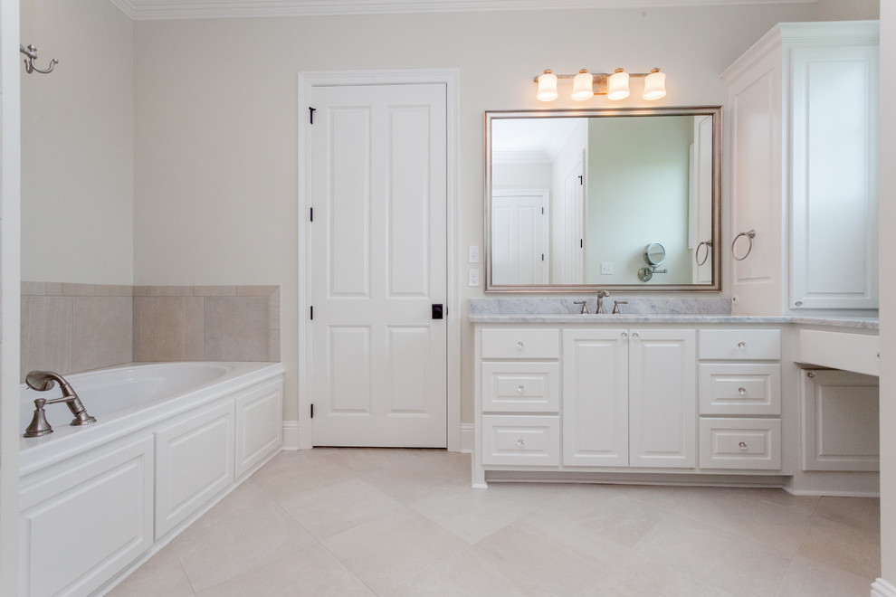 Mid-sized elegant master white tile and ceramic tile ceramic tile bathroom photo in New Orleans with raised-panel cabinets, white cabinets, beige walls, a drop-in sink and marble countertops