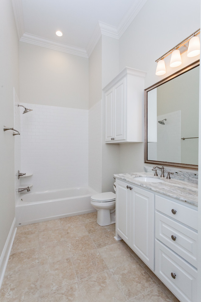 Bathroom - mid-sized traditional kids' white tile and ceramic tile ceramic tile bathroom idea in New Orleans with raised-panel cabinets, white cabinets, a one-piece toilet, beige walls, a drop-in sink and marble countertops