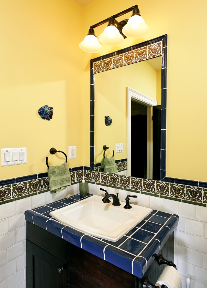 Idee per una stanza da bagno con doccia mediterranea di medie dimensioni con ante con bugna sagomata, ante in legno bruno, top piastrellato, doccia alcova, piastrelle blu, piastrelle in gres porcellanato e pareti gialle