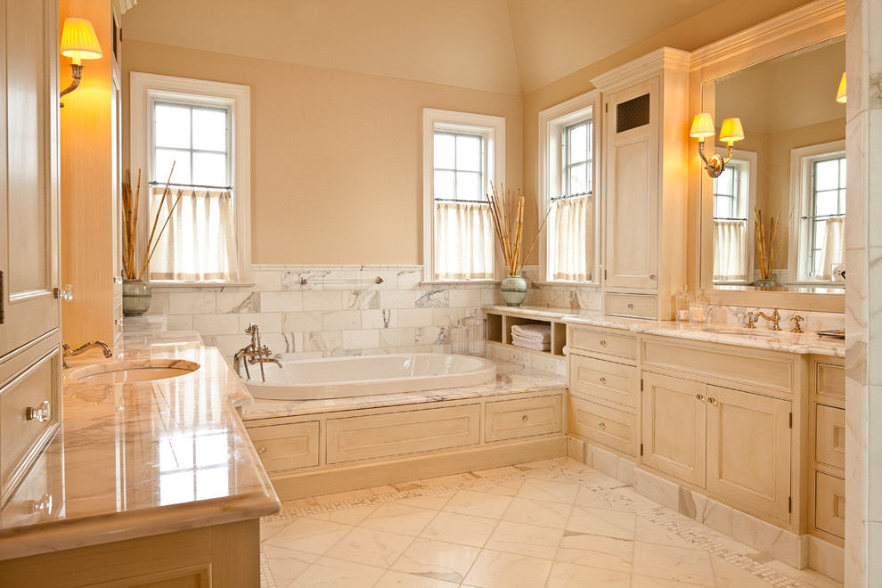 Foto på ett vintage en-suite badrum, med ett platsbyggt badkar, marmorgolv, ett undermonterad handfat, luckor med profilerade fronter, skåp i ljust trä, vit kakel, marmorkakel, beige väggar och vitt golv