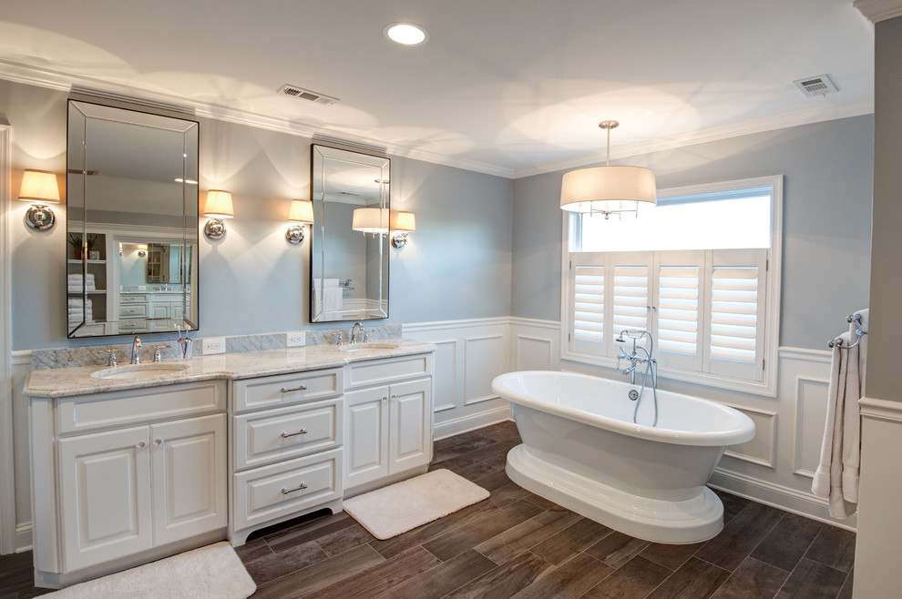 Example of a large classic master gray tile and stone tile porcelain tile freestanding bathtub design in DC Metro with raised-panel cabinets, white cabinets, a two-piece toilet, gray walls, an undermount sink and marble countertops