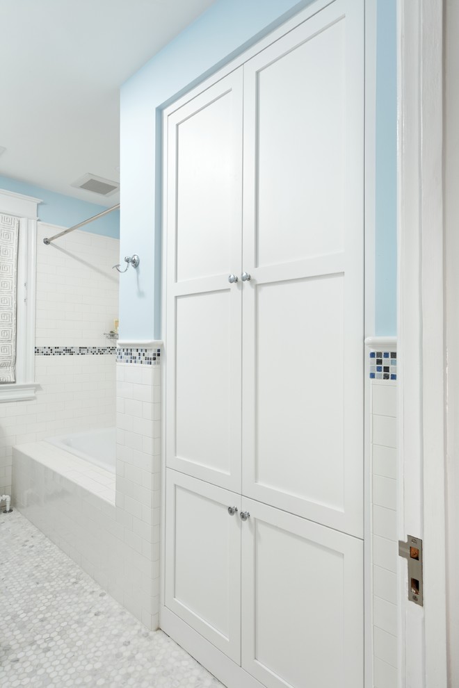 Klassisk inredning av ett mellanstort badrum, med ett badkar i en alkov, en dusch/badkar-kombination, en toalettstol med separat cisternkåpa, vit kakel, tunnelbanekakel, blå väggar, mosaikgolv och ett piedestal handfat